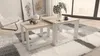 A living room scene with nesting coffee tables on a rug, next to a chair and artwork. Produktbild-Vorschau