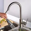 A hand is shown pulling the spray head of a kitchen faucet over a sink, with broccoli on a cutting board in the background. Náhľad obrázku produktu