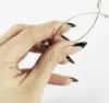 A hand with black-tipped nails holds a metal kitchen utensil. Produktbild-Vorschau