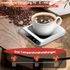A coffee cup sits on a white electric mug warmer next to a pile of coffee beans. Produktbild-Vorschau