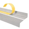 A close-up of a gray stair nosing profile with yellow protective tape being peeled off. Anteprima dell’immagine prodotto