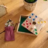 A wooden board game with colorful playing pieces and a bag of colorful stones on a wooden surface. Produktbild-Vorschau