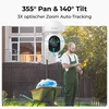 A man in green overalls is working in a garden next to a wheelbarrow, with a security camera mounted on a house in the background. Produktbild-Vorschau