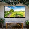 A projector screen displaying a landscape scene is mounted on a concrete wall above a wooden bench, with plants on either side. Voir les images du produit