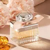 A perfume bottle is displayed with flowers and amber-like objects. Anteprima dell’immagine prodotto