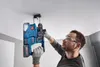 A man is drilling into a ceiling with a power drill. Voir les images du produit