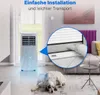 A portable air conditioner is shown in a living room setting with a dog lying on the floor. Podgląd zdjęcia produktu