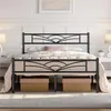 A black metal bed frame with a decorative headboard and footboard, set up in a bedroom with bedding. Produktbild-Vorschau