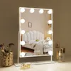 A vanity mirror with lights on a dresser, with makeup brushes and bottles. Podgląd zdjęcia produktu