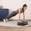 A woman is doing a plank exercise on a vibration plate in a room. Náhľad obrázku produktu