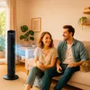A couple relaxing on a couch in a living room with a tower fan. Produktbild-Vorschau
