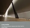 A close-up shot of a vacuum cleaner crevice tool being used to clean under a piece of furniture. Produktbild-Vorschau