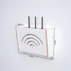 A white router storage box with a wooden trim is mounted on a white wall. The box has a cut-out design resembling Wi-Fi signals on its front panel. Dimensions are indicated with measurement lines and text. Anteprima dell’immagine prodotto