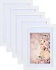 A stack of white picture frames with one frame displaying a portrait of a woman adorned with flowers. Produktbild-Vorschau