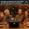 A family is gathered around a table, enjoying a meal with a pot in the center. Produktbild-Vorschau
