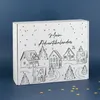 A white cardboard advent calendar with a line art drawing of a winter village and trees, set against a dark blue background. Small gold star confetti is scattered on the surface in front of the calendar. Produktbild-Vorschau