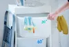 A person's hand is shown reaching for a white laundry bin with temperature markings, suggesting a laundry or organization context. Podgląd zdjęcia produktu