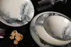A close-up overhead shot of a set of plates and a bowl with a marble-like pattern, along with a wine glass and some cereal. Anteprima dell’immagine prodotto