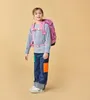 A young girl wearing a backpack and jeans stands against a plain background. Náhled obrázku produktu