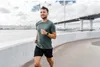 A man is jogging on a path next to a body of water, with a bridge in the background. Náhled obrázku produktu