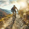 A person is riding a mountain bike on a dirt trail in a mountainous area during the day. Podgląd zdjęcia produktu