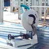 A metal cutting saw is set up on a construction site, with stacks of metal framing materials in the foreground and background. Anteprima dell’immagine prodotto