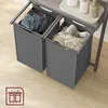 Two grey laundry baskets are pulled out from a grey shelf unit, one containing blue clothes and the other containing beige clothes. Produktbild-Vorschau