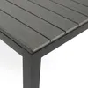 A close-up view of a table corner, showing the slatted tabletop and the black metal frame and leg. Náhled obrázku produktu