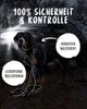 A large dog wearing a black harness with reflective strips stands in front of a car at night, with headlights on. Produktbild-Vorschau