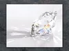 A close-up of a diamond on a white surface with light reflections. Produktbild-Vorschau