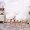 Two white chairs with wooden legs are placed on a patterned rug in a room with a lamp and a cabinet. Voir les images du produit