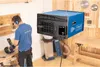 A man is working in a workshop with a dust collector and an air purifier hanging from the ceiling. Voir les images du produit