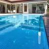 A thermometer floats in a swimming pool next to a modern villa. Produktbild-Vorschau