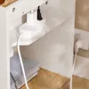 A close-up view of a white power strip with two plugs inserted, connected to a white cable, resting on a shelf. Produktbild-Vorschau