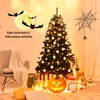 A decorated Christmas tree with Halloween-themed decorations, including bats and a spiderweb, set up in a cozy room with a chair and pillows. Anteprima dell’immagine prodotto