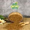 A bowl of flax seeds with a wooden scoop, a flower, and some greenery on a burlap surface, with a grey textured background. Produktbild-Vorschau