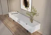 A modern white TV stand with books and a vase of flowers on top, placed in a room with wooden flooring and a painting on the wall. Produktbild-Vorschau