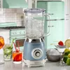 A vintage-style blue blender filled with ice sits on a kitchen counter, surrounded by cocktails and fruit. Anteprima dell’immagine prodotto