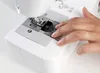 A close-up shot of a person's hand interacting with a sewing machine. Produktbild-Vorschau