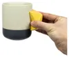 Keramiktasse "Climbing Mug Evo" von YY Vertical mit Klettergriff; in Hand gehalten; beige mit schwarzem Boden. Podgląd zdjęcia produktu