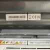 A close-up view of a label on a printer, showing serial number, certification marks, and support website. Produktbild-Vorschau