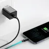 A black USB-C charger plugged into a white wall socket, connected by a black cable to a smartphone that is 50% charged. Produktbild-Vorschau