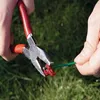 Hands using pliers to connect a green wire to a red connector, with grass in the background. Produktbild-Vorschau