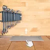 A set of wrenches mounted on a wall above a retractable power outlet on a wooden surface. Produktbild-Vorschau