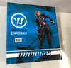 The image shows the front of a Warrior Youth Hockey Starter Kit box, featuring a young hockey player in full gear. Produktbild-Vorschau