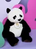 A plush panda toy is sitting in front of a colorful, abstract background. Anteprima dell’immagine prodotto