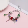 Silbernes Charm-Armband mit verschiedenen Weihnachtsmotiven, darunter ein grüner Weihnachtsbaum, rot-weißes Zuckerrohr, silberne Schneeflocke und eine funkelnde silberne Weihnachtsmannmütze Voir les images du produit