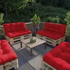 Outdoor patio furniture set made of wooden pallets with red cushions, arranged around a coffee table on a deck with greenery in the background. Voir les images du produit