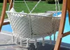 A hammock chair with cushions is hanging from a wooden frame next to a swimming pool. Produktbild-Vorschau