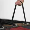 A close-up of a finger holding two black elastic cords attached to a red and brown plaid fabric with metal grommets. Produktbild-Vorschau
